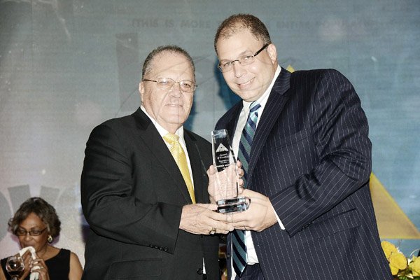 Rudolph Brown/Photographer
The Honourable Arnold Foote OJ, CD, JP, Founder of Advertising and Marketing Ltd. (AdMark) presents JJ Foote Jnr. CEO/CCO with an Award of Excellence at the company’s 50th Anniversary Banquet at  at the Jamaica Pegasus on Tuesday, April 14
