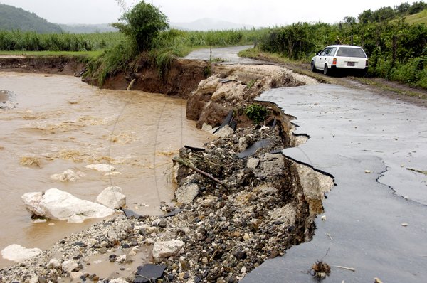 Ricardo Makyn/Staff Photographer.
A Motorist gingerly drives on what's left of the main Road which leads to Guy's Hill St Catherine  due to the heavy Rains on Thursday 30.9.2010.