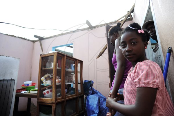 Ricardo Makyn/Staff Photographer 
From left Alashia Parker with Daughter Calecia Gibson and Grandfather Glendford Parker in thier Home that is now roofless in    Manchioneal Portland  due to  the passage of  the Hurricane Sandy