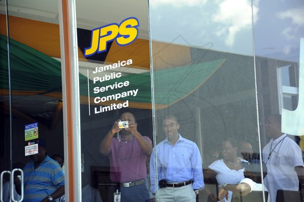 Norman Grindley/Chief Photographer
A man takes photos from inside the Jamaica Public service JPS corporate office, in New Kingston St Andrew, during a black a out Friday protesters yesterday.