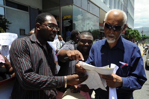 Norman Grindley/Chief Photographer
Junior Rose, (left) president of the PNPYO Ricardo James, General Secretary PNPYO and K.D Knight looking over some light bills during a black their black out Friday protest in New Kingston St. Andrew yesterday