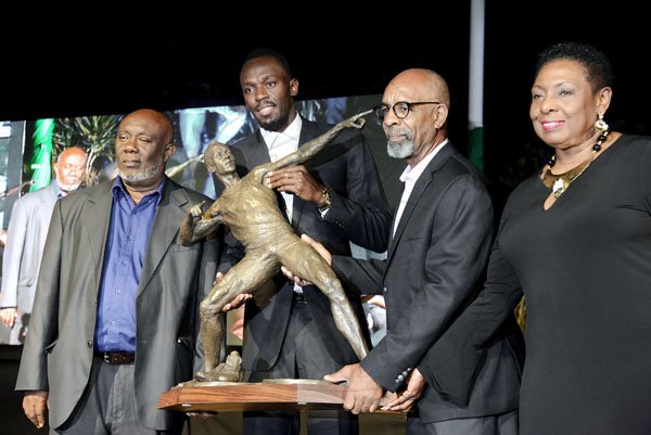 Rudolph Brown/Photographer<\n>Sculptor Basil Watson, (second right) presents statue to Usain Bolt while coach Glen Mills, (left) and Olivia Babsy Grange, Minister of Culture, Gender, Entertainment and Sport looks on at the Unveiling of Usain Bolt statue at the National Stadium on Sunday, December 3, 2017 *** Local Caption *** @Normal:Sculptor Basil Watson (second right), presents Usain Bolt (center) with a miniature version of his statue, while coach Glen Mills, (left) and Sports Minister Olivia 'Babsy' Grange look on.
