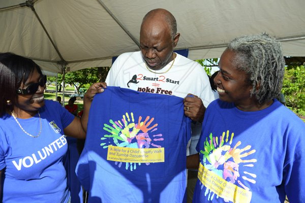 Rudolph Brown/Photographer
Karen Watson-Pink, (left) manager corporate communications and brand, RBC Bank and Andrene Gordon- Garricks give Dr Fenton Ferguson, Minister of Health a shirt at the RBC Royal Bank Caribbean Children's Cancer Fund, " A Mile for a Child" join with family and friends participate in a charity walk and a fun class of Zumba and aerobics session at the Emancipation Park in New Kingston on Saturday, September 8-2012