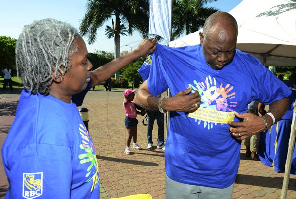 Rudolph Brown/Photographer
Andrene Gordon- Garricks help Dr Fenton Ferguson, Minister of Health fit shirt at the RBC Royal Bank Caribbean Children's Cancer Fund, " A Mile for a Child" join with family and friends participate in a charity walk and a fun class of Zumba and aerobics session at the Emancipation Park in New Kingston on Saturday, September 8-2012