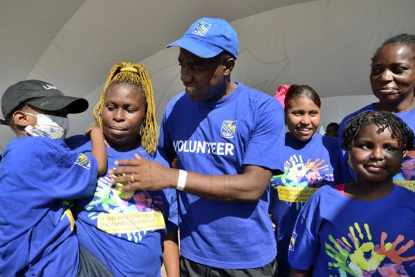 Rudolph Brown/Photographer
Roger Cogle, Market Head, Personal Banking at RBC Royal Bank (Jamaica) speaks with Tafari Forte and his mother Sophia Lewis, (left) while some of the cancer survivors children looks on at the RBC Royal Bank Caribbean Children's Cancer Fund, " A Mile for a Child" join with family and friends participate in a charity walk and a fun class of Zumba and aerobics session at the Emancipation Park in New Kingston on Saturday, September 8-2012