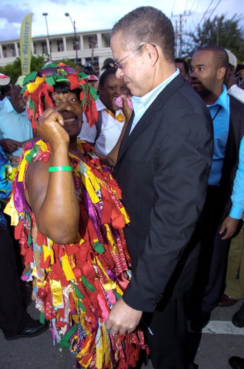 Norman Grindley/Chief Photographer
A jonkanoo performer grabs Prime Minister Bruce Golding for a dance during Christmas in the City activities on Sutton Street, downtown Kingston yesterday.