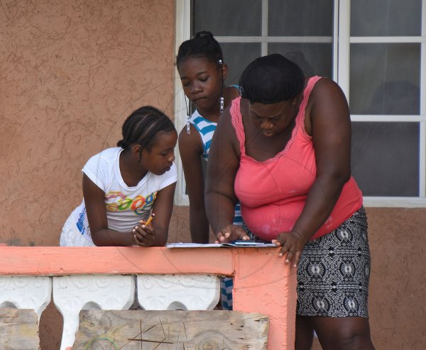 Grade four student at Golden Grove Primary and Infant School in St Thomas, Kheniece Thompson (left), gets help from Tamara Russell (right), her godmother, to access schoolwork from a cell phone shortly after it was sent by her teacher recently. Looking on is Tamila Rowe, student of Happy Grove High School in Portland. Since the closure of schools islandwide because of the COVID-19 pandemic, students and teachers have increasingly used online platforms for education.