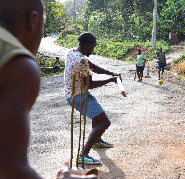 Young men in Point Hill, St Catherine, play a game of cricket in the streets to help pass the time as COVID-19 has turned many districts and villages into ghost towns.