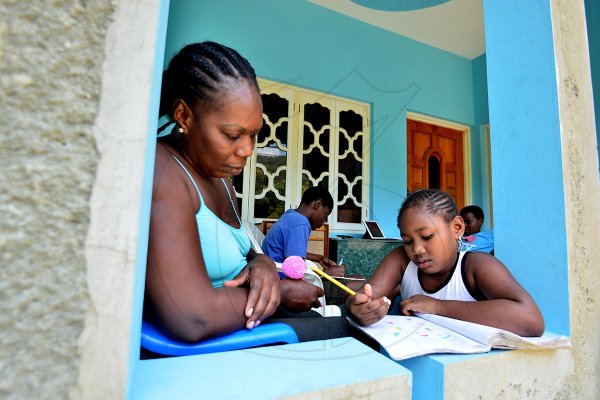 Patricia Smith assists her six-year-old daughter, maurissa, with some schoolwork yesterday. With the closure of schools due tot he coronavirus pandemic, many parents are now supervising their children's studies at home