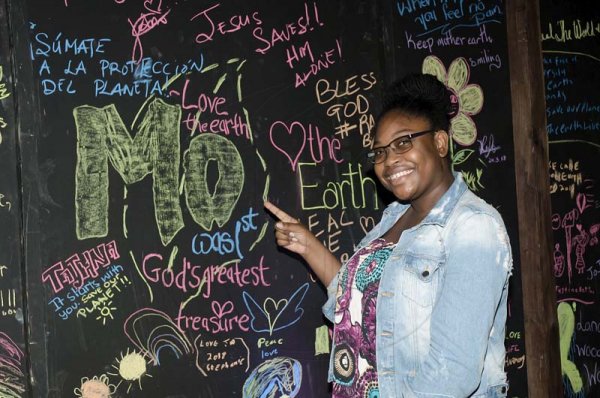 Shorn Hector/Photographer   Monique Moncrieffe smiles proudly beside her piece on the Gleaner Company's chalkboard at the Earth Hour concert held at Ranny William Entertainment Centre on March 25, 2018