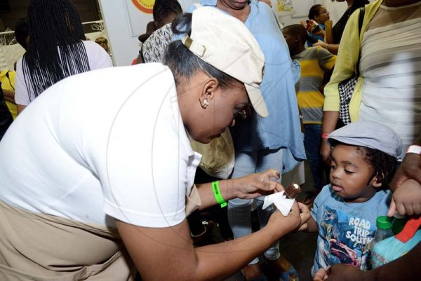 Rudolph Brown/ Photographer<\n>Saskeia Wallace team member of Chocolate Dreams give chocolate to little Nathaniel Bryan at the JEA JMA Expo Jamaica at the National Indoor Sports Centre and the National Arena on Sunday April 22, 2018<\n><\n><\n>