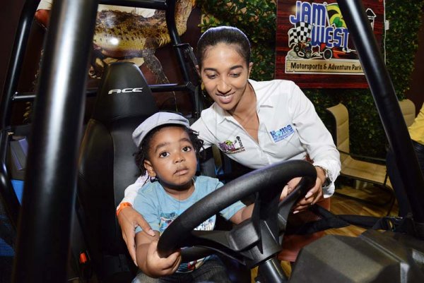 Rudolph Brown/ Photographer<\n>Shyian Gordon, managing director of Jamwest, show little Nathaniel Bryan how an all-terrain vehicle model works inside Jamwest's booth at Expo Jamaica 2018 yesterday.