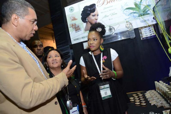 Rudolph Brown/ PhotographerKareen Lamme, (right) licensed Beauuty Therapist of Bute Cosmetics show  Prime Minister Andrew Holness her product while Michelle Chong, (centre) President, Jamaica Exporters' Association (JEA) during a tour of the JEA JMA Expo Jamaica at the National Indoor Sports Centre and the National Arena on Sunday April 22, 2018