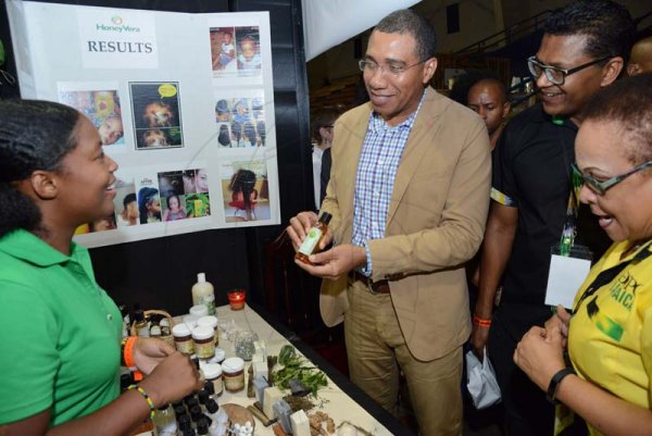 Rudolph Brown/ PhotographerChristal-Ann Thompson, (left) Founder and CEO of Honey Vera, give the Prime Minister Andrew Holness, (centre) one of her Hemp product while Doreen Frankson, (right), former President of the Jamaica Manufacturers Association (JMA) and Richard Pandolie, Deputy President of JMA during a tour of the JEA JMA Expo Jamaica at the National Indoor Sports Centre and the National Arena on Sunday April 22, 2018
