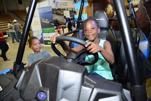 Rudolph Brown/ PhotographerBrayden Nugent and Brianna Nugent try out the Jam West car at the JEA JMA Expo Jamaica at the National Indoor Sports Centre and the National Arena on Sunday April 22, 2018