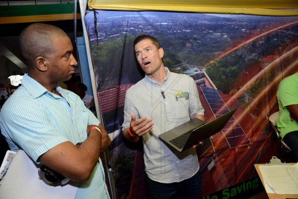 Rudolph Brown/ PhotographerJason Robinson, (right) CEO of Solarbuzz Jamaica show Major O' Neil Bogle how hie company system work at the JEA JMA Expo Jamaica at the National Indoor Sports Centre and the National Arena on Sunday April 22, 2018