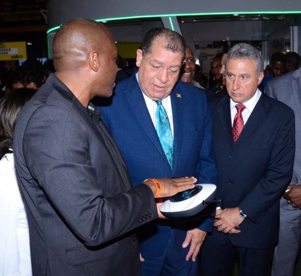 Shorn Hector/Photographer   Brain Bennette-Easy General Manger Digicel Jamaica (left) ishowcasing the lates in technolofy that digicel has to over to The Hon. Audley Shaw and Metry Seaga at Expo Jamaica 2018 Opening Ceremony at the National Indoor Sports Complex on April 19 2018