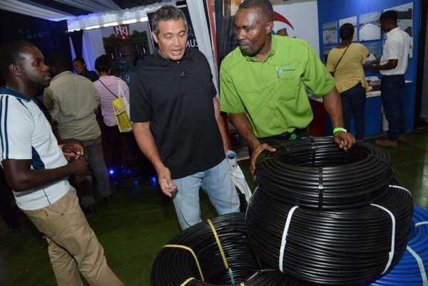 Rudolph Brown/ Photographer
Paul Allen, (right) of Jamaica Drip Irrigation Isratech Waterworks show his company hose st the JEA JMA Expo Jamaica at the National Indoor Sports Centre and the National Arena on Friday April 20, 2018