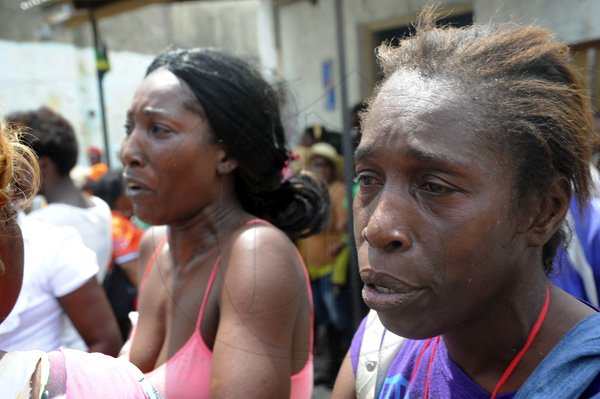 Norman Grindley/Chief Photographer
Residents discuss their next move after a  major fire  destroyed several houses on Regent Street in downtown Kingston yesterday. Three fire units and a water truck arrived on the scene as fire personnel tried to contain the blaze.