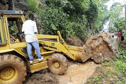 Ian Allen/Photographer
A backhoe clears a huge boulder from a landslide during heavy rains from Tropical Storm Nicole that  blocked section Manning Hills road in Upper St.Andrew.