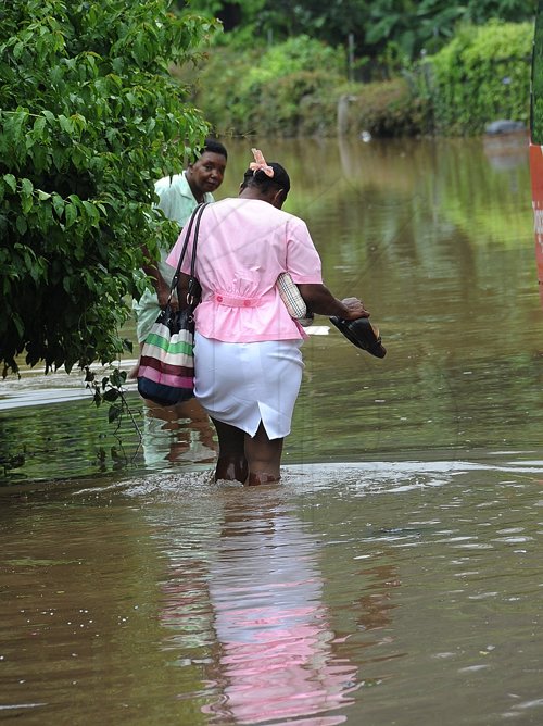 Ian Allen/Photographer
A Nurse makes her through murky waters which was caused by blocked drains along Stillwell Road in Upper St.Andrew after rains from Tropical Storm Nicole lashed the Island wednesday.