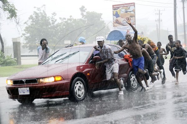Rudolph Brown/Photographer
These young men push this motor vehicle through the rain on Marescaux Road near Heroes Circle, Kingston, yesterday.