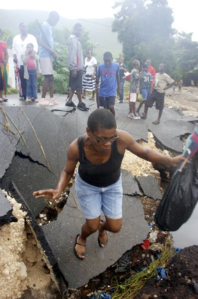 Norman Grindley/Chief Photographer
This resident of McGregor Gully in Kingston balances as she made her way yesterday along what was a road in the community which has been destroyed by flood waters.
