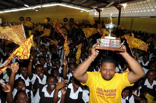 Norman Grindley /Chief Photographer
Holmwood track team chef Laurel Green lifts the championship trophy in front of screaming students during the school's celebration of their recent ISSA/GraceKennedy Boys' and Girls' Championships inside the auditorium yesteday.
