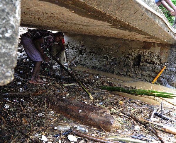 Ricardo Makyn/Staff Photographer
 Residents feverishly trying to remove Debris from the Flat Bridge in the Bog Walk Gorge in St Catherine on Monday 27.8.2012