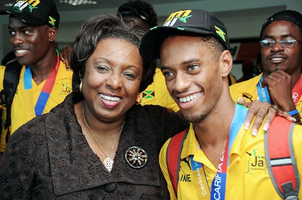 Ian Allen/Photographer
Sports Minister Olivia 'Babsy' Grange (second right) hugs double gold medallist, middle-distance king Kemoy Campbell, as members Jamaica's Carifta Games contingent returned home at the Norman Manley International Airport yesterday.