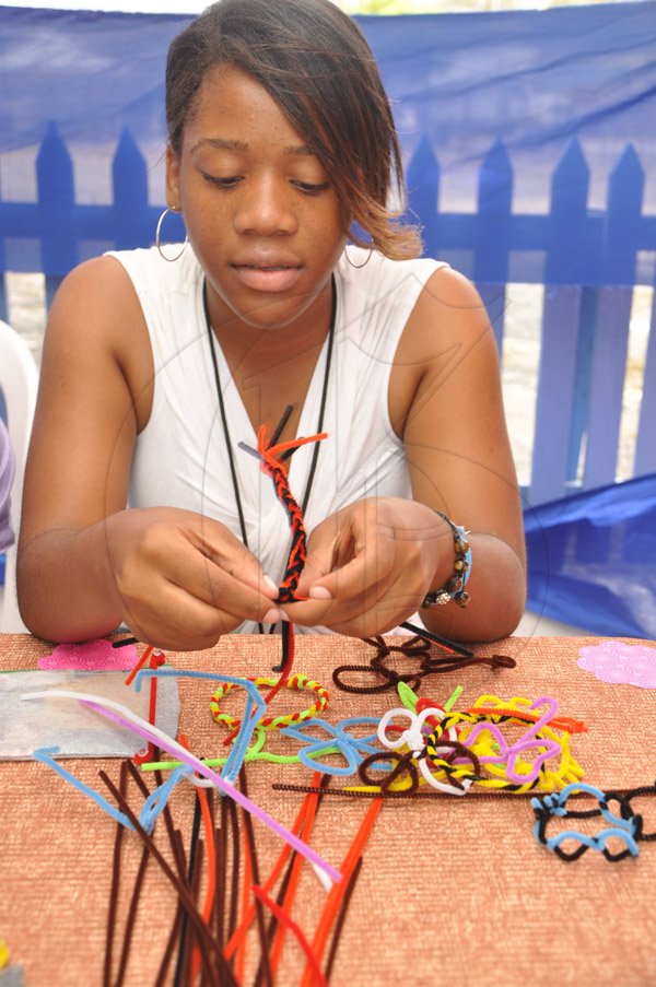 Jermaine Barnaby/Photographer
Georgia Bailey of the Ardenne High School in the process of handcrafting some braclets at the Eco-Pure booth during the Jampreneurs Expo & Summer Jam at the  Ranny Williams Entertainment Centre on  Saturday, July 5, 2014.