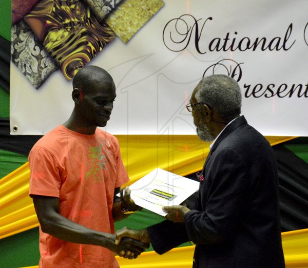 Winston Sill/Freelance Photographer
The Jamaica Cultural Development Commission (JCDC) presents Jamaica Visual Arts Competition Awards and Exhibition, held at the Jamaica Conference Centre, Downtown, Kingston on Sunday December 22, 2013. Here  Errol Harvey (right) presents Jermaine Barnaby (left) with is award.