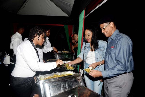 Lionel Rookwood/Photographer<\n>Chairman of JMMB Group, Archibald Campbell and Fornia Young dig right into nyammings.<\n>