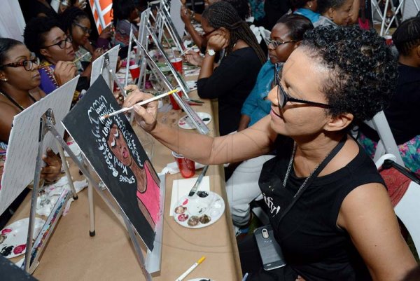 Rudolph Brown/ Photographer<\n>JMMB IWD sip and paint at JMMB 6 Haughton Terrace Kingston on Thursday, March 8, 2018<\n><\n>Lystra Sharp writes words of encouragment within the hair of her painting.