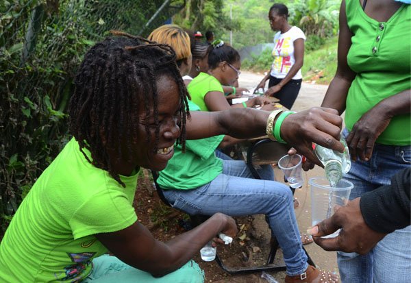 Rudolph Brown/Photographer
JLP supporter share a bottle of rum at a polling station in Red Halls on Local Government election on Monday, March 26-2012