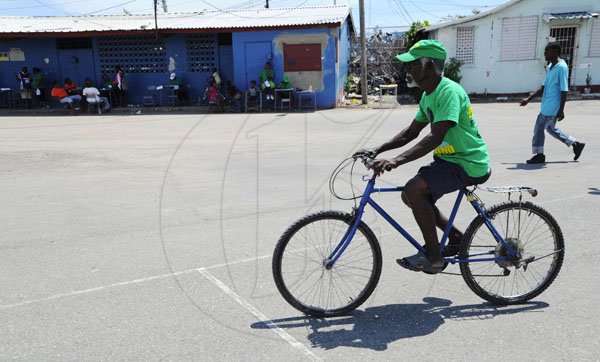 Ricardo Makyn/Staff Photographer
A JLP rides His Bicyle to the Polling Station at the Denham Town High School  on Election Day