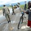 Rudolph Brown/Photographer
This man carry his bicycle across while the JDF Soldiers use a bulldozer to remove a pile up of sand and silt from the palisadoes main road in Kingston from High tides and high winds, related to Hurricane Matthew on Tuesday, October 4, 2016