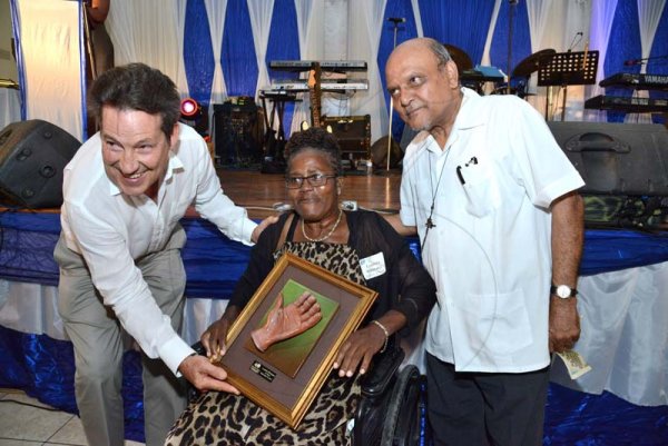 Rudolph Brown/PhotographerRev. Msgr. Gregory Ramissoon, (right) Founder of Mustard Seed and Bob Fowler, board member presents award for 34 years of service to Leadora Whittaker at the Mustard Seed communities 40th anniversary awards and banquet at the St. Peter and Paul Church Hall on Saturday, September 8, 2018