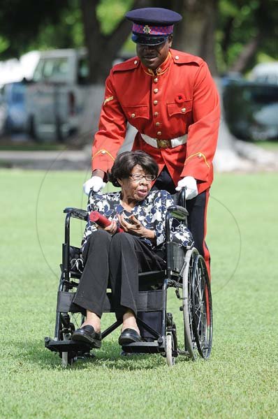 Lionel Rookwood/Photographer Dr.Lucille Buchanan is escorted by a JDF soldier after being awarded the Order of Distinction in the rank of officer at the Presentation of National Honours and Awards held at King's House on October 15th,2018.