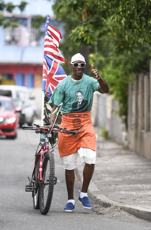 Alfred Sparks gives the thumbs up  while walking along Slipe Pen road attired in the colours of the two main political parties,  the fifty none year old say's he's making a statement to ordinary Jamaicans that they should not have the mentality that it's party over country but the total opposite and to live as one no matter our political differences.