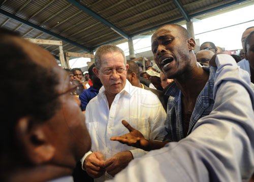 Ricardo Makyn/Staff Photographer.
Left Michael Webb Arrears/Data resarch Manager KSAC Markets Department listens to a plea by a distraught Christopher Cowans a Market Vendor while Prime Minister Bruce Golding looks on the Prime Minister was on a Tour of the Coronation Market with a delegation from the private sector and other Groups on Thursday 10.6.2010.