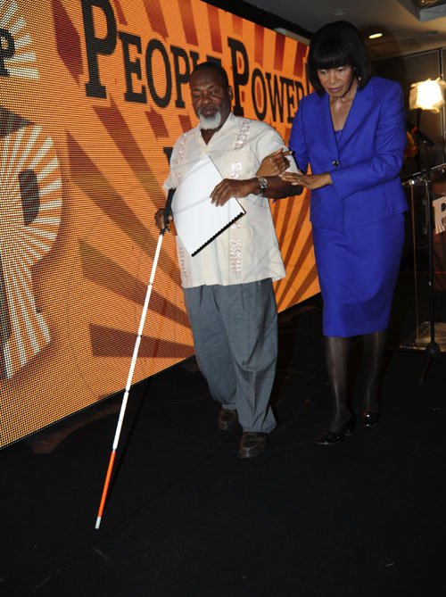 Norman Grindley/Chief Photographer
Portia Simpson-Miller (right) led Derrick Palmer off stage after she present him a copy of the Manifesto in breile at the launch of the People's National Party manifesto at the Wyndham hotel in St. Andrew yesterday.