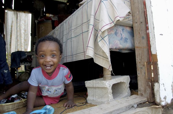 Ricardo Makyn/Staff Photographer.
One year-old Jordane McKenzie sits beside a bed that has been put on blocks in preparation for the passage of Tropical Storm Tomas and the rains that will accompany the system, at his home in New Haven, St Andrew, yesterday.