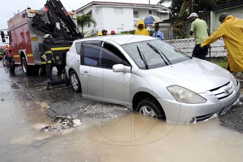 Norman Grindley/Chief Photographer
Firefighters respond to a call to assist a motorist who got stuck in a broken main on Palmoral Avenue in Mona Heights after heavy rains in St. Andrew yesterday.