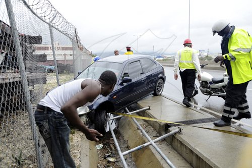 Ricardo Makyn/Staff Photographer
Police and passersby look at this Honda Civic Motor Car got out of control while it was driven in a Westerly direction on Marcus Garvey Drive hitting down guard Rail in the vicinity of the Tinson Pen Aerodrome on Tuesday 7.6.2011