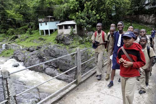 Norman Grindley/Chief Photographer
Students from Grove Primary in St Andrew cross a bridge from school yesterday. The students were sent home early because of the weather conditions.