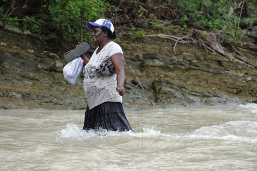 Ricardo Makyn/Staff Photographer
Memry Edie 56 Years Old carefully walks in the River to get Home across the Yallahs River in the Gordon Castle Distrcit Llandewey St Thomas,where a section of the Wooden Bridge as washed away and residents have to walk through the River in order to get Home.