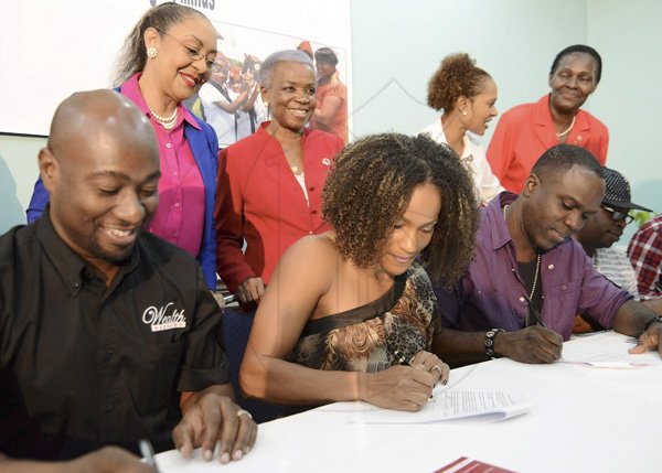 Rudolph Brown/Photographer
Bridgette Foster Hylton, (centre)  Garth Walker, (left) and Ity, (right) signing the Red Cross membership form while looking on from left are Dr. Marion Bullock-DuCasse, director, Health Ministry's Emergency Disaster Management and Special Services, Yvonne Clarke, Director General of Red Cross, Allison Watson and Lois Hue at the Jamaica Red Cross 2012 Launch Membership Campaign media briefing at Knutsford Court Hotel on Monday, October 8, 2012