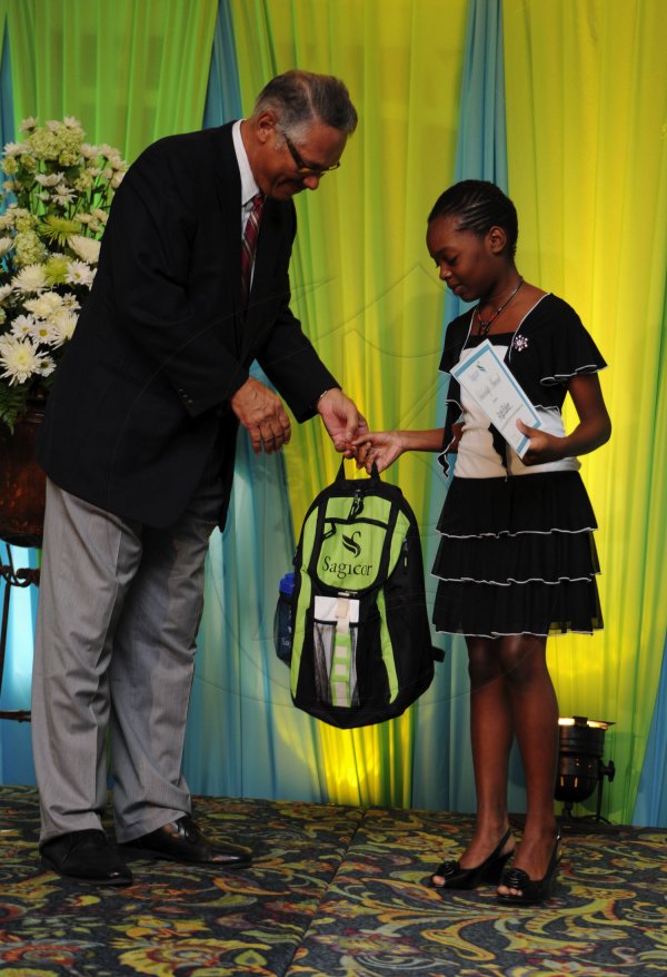 Ricardo Makyn/Staff Photographer
Errol McKenzie Executive Vice President Sagicor presents Angel Baker who will be attending St Jago High  School   at the Sagicor annual GSAT awards ceremony at the Knutsford Court Hotel on Thursday 23.8.2012