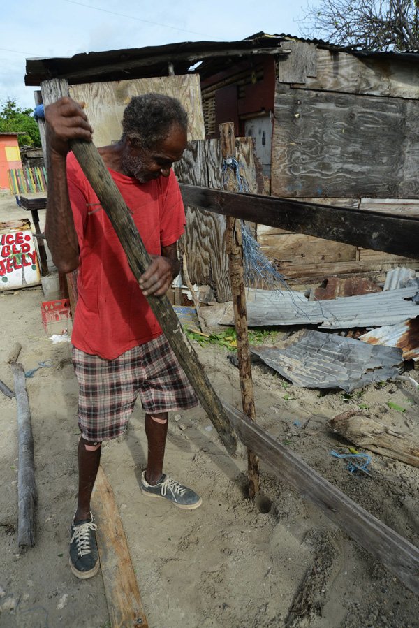 Rudolph Brown/Photographer
Oswald Williams tries to repair his fence after his one-bedroom house was flattened by Hurricane Sandy.

 passes through Jamaica on damage properties on Thursday, October 25, 2012
